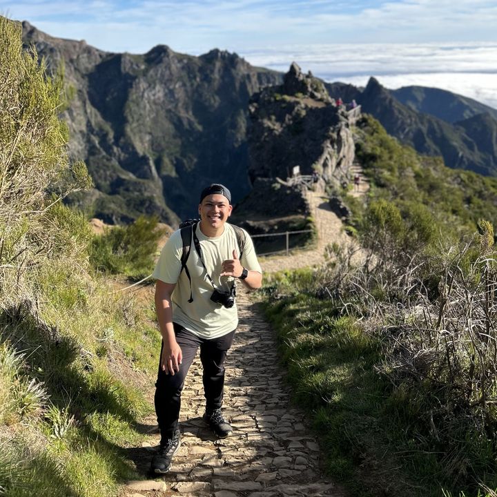 Matt hiking a stone path along a mountain ridge above the clouds